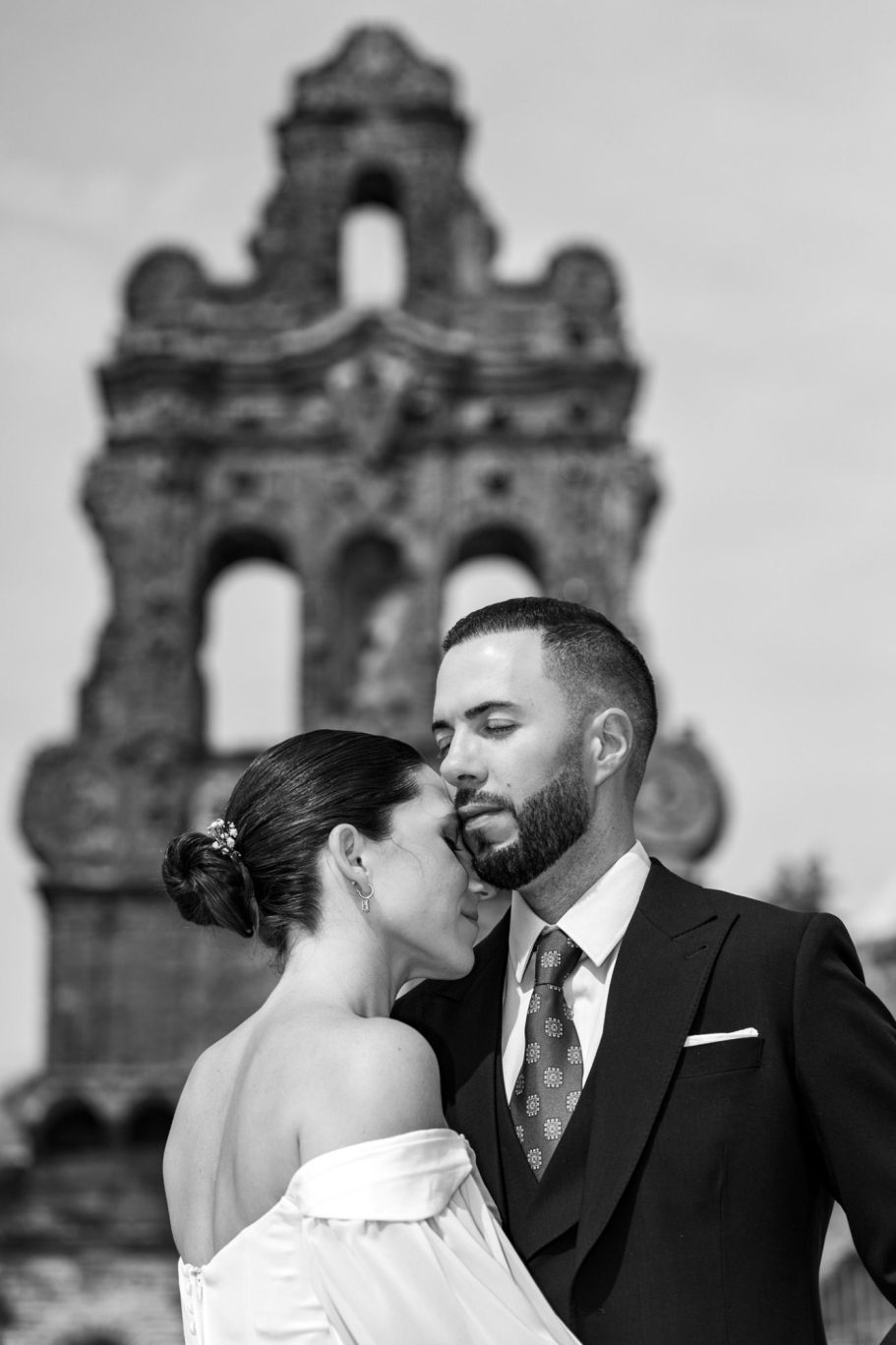 Pareja de novios compartiendo un momento íntimo frente a una arquitectura antigua.