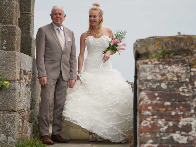 Pareja de novios posando juntos, ella en vestido de boda y él en traje formal.