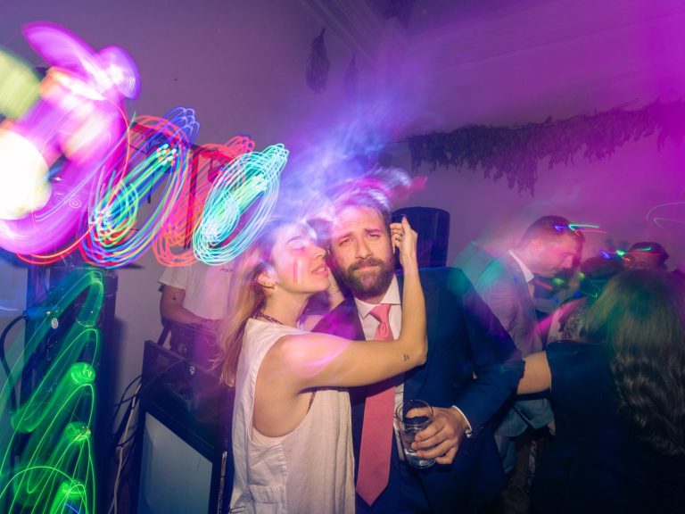 Pareja disfrutando de una fiesta con luces de colores brillantes y ambiente festivo.