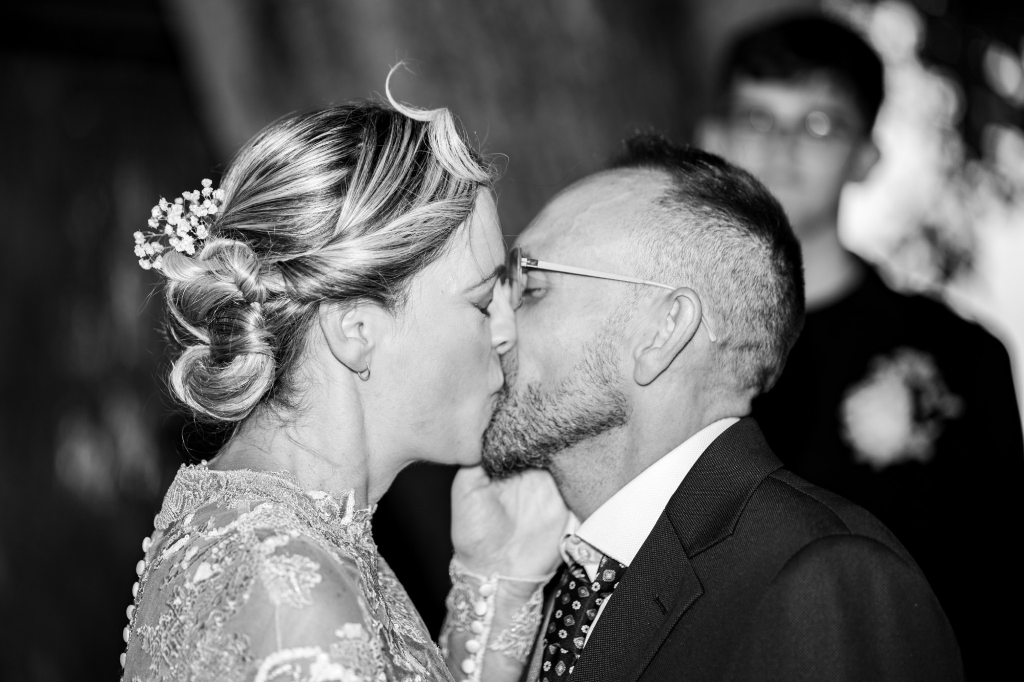 Pareja de novios besándose durante la ceremonia, rodeados de un ambiente íntimo.