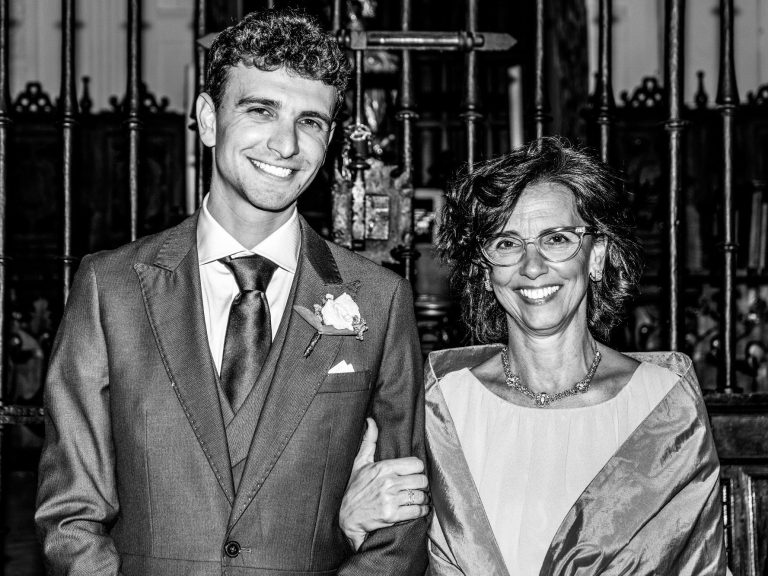 Una madre y su hijo de camino al altar sonriente vestida elegantemente en un entorno nupcial.