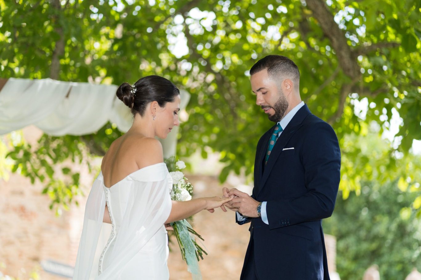 Pareja intercambiando anillos durante una ceremonia de matrimonio al aire libre.