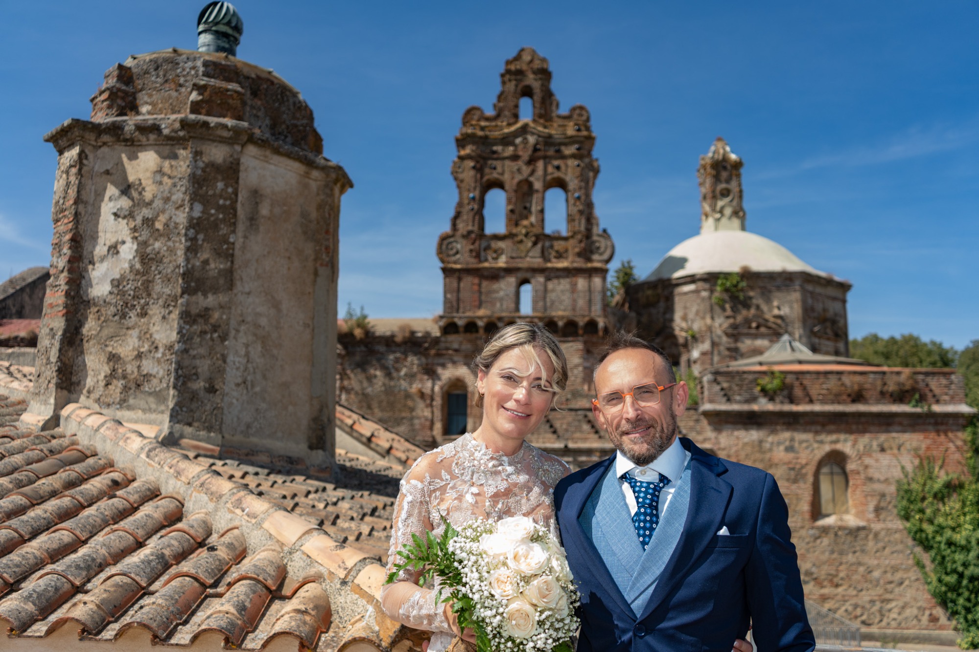 Pareja de recién casados posando con edificios históricos al fondo.