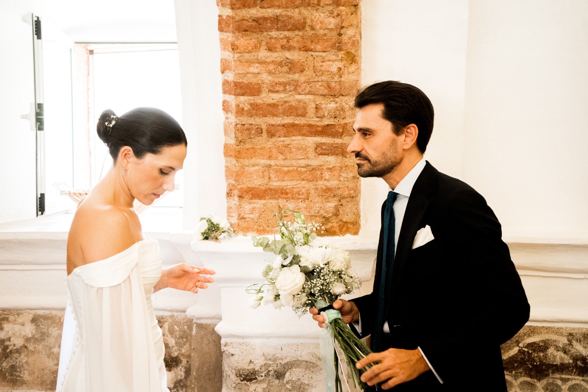 Pareja elegante en un ambiente clásico, ella con ramo y él sosteniendo champán.