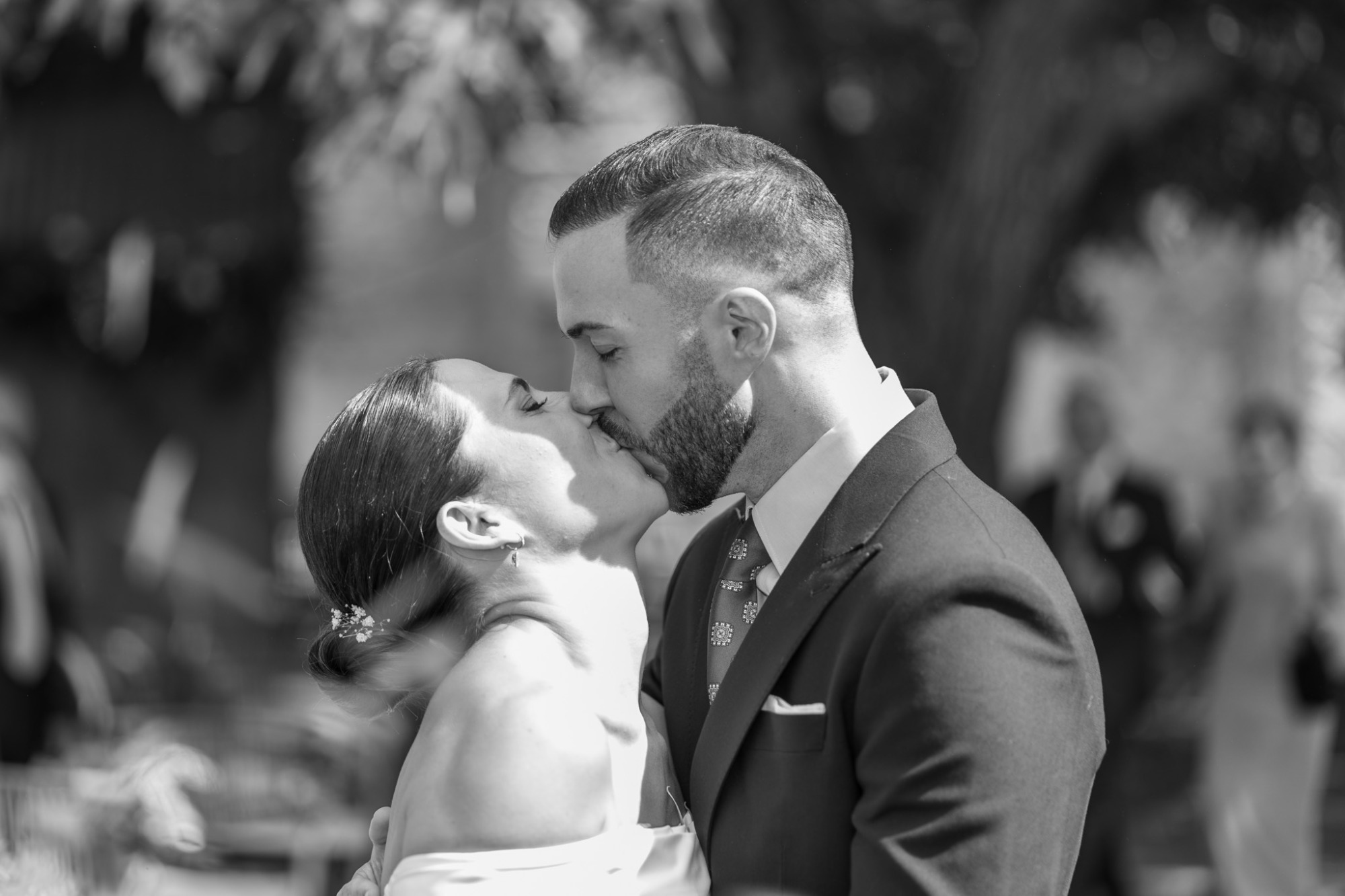 Pareja romántica compartiendo un beso en un ambiente festivo y natural.