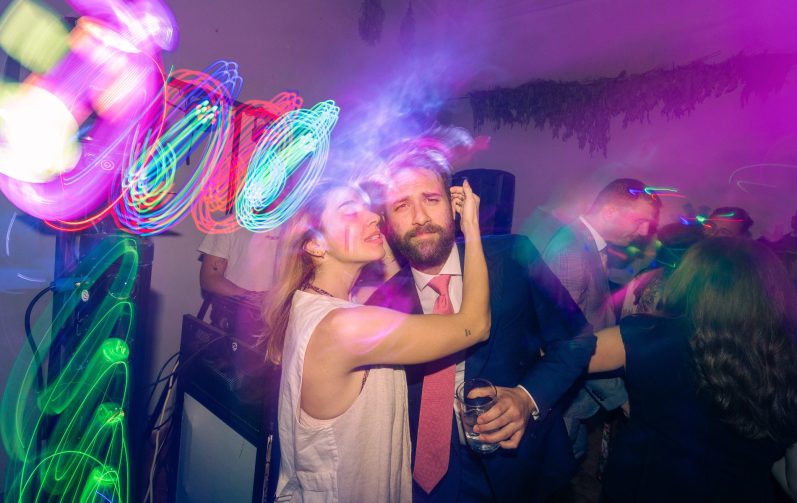 Pareja sonriendo y celebrando en una fiesta con luces de colores.