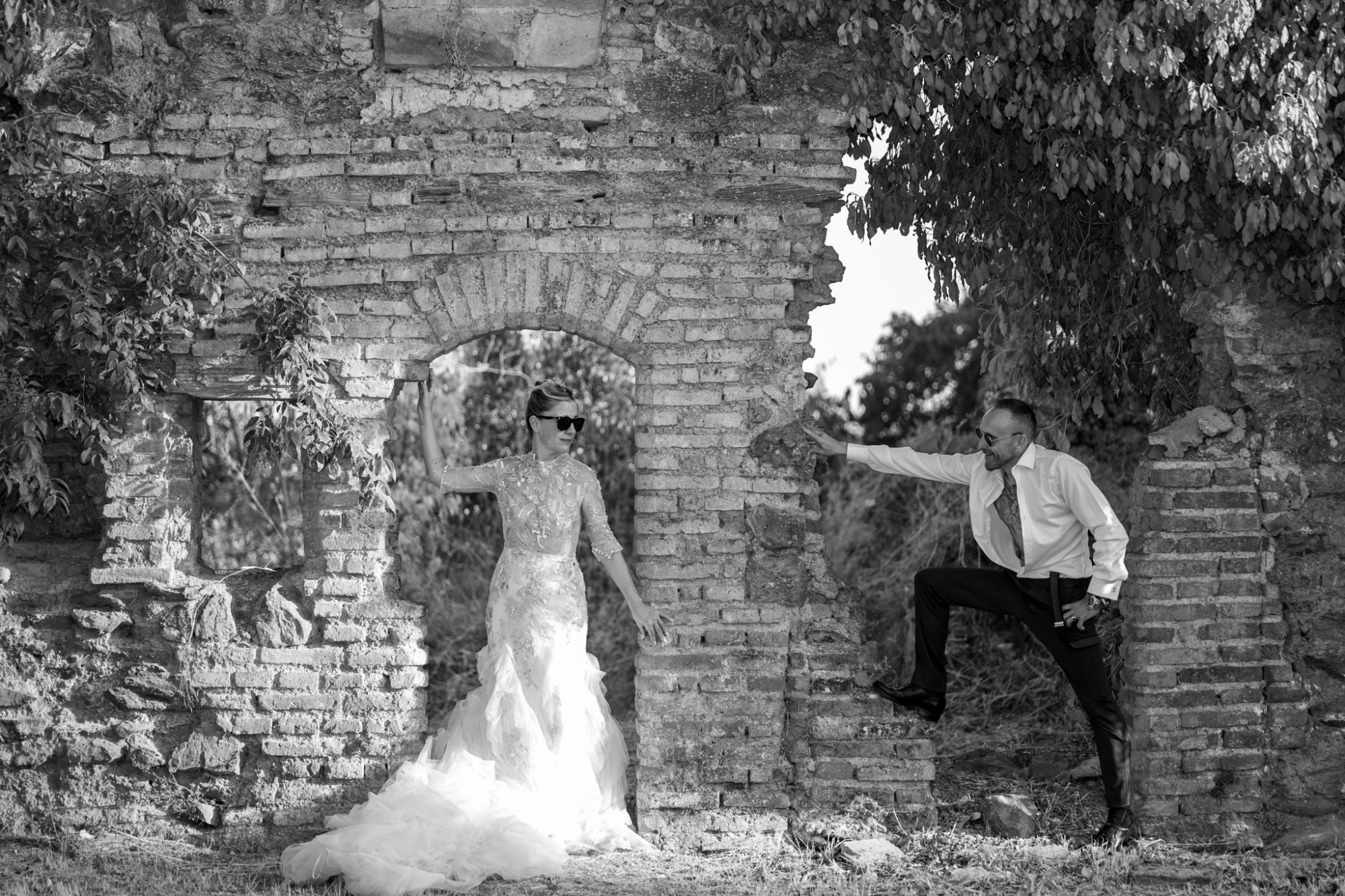 Pareja de novios posando en una pared de ladrillos, fondo natural.