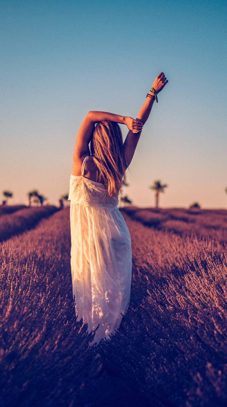 Mujer con vestido blanco en un campo de lavanda al atardecer.